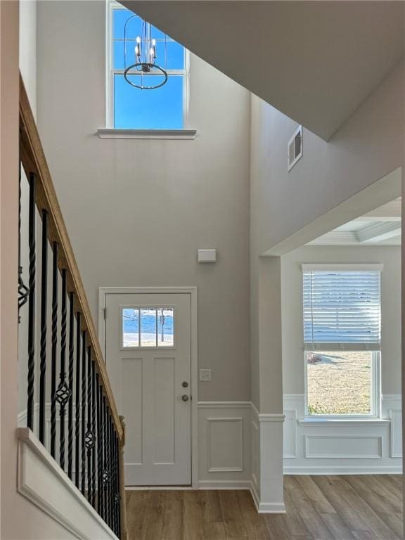 foyer entrance with light wood-type flooring, an inviting chandelier, and a towering ceiling