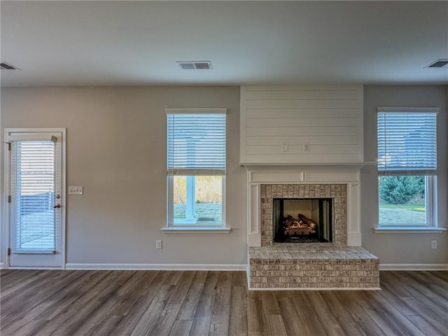 unfurnished living room featuring a brick fireplace and hardwood / wood-style floors