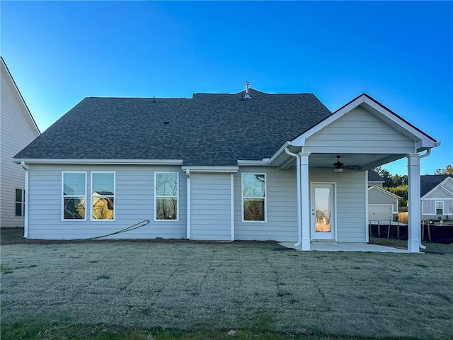 rear view of property with ceiling fan, a patio area, and a lawn