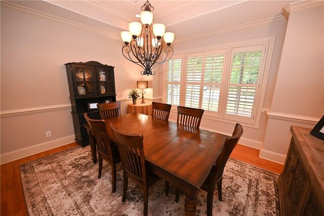 dining area featuring ornamental molding, hardwood / wood-style flooring, and a notable chandelier