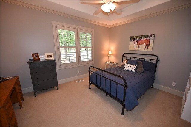 carpeted bedroom featuring a tray ceiling, ceiling fan, and ornamental molding