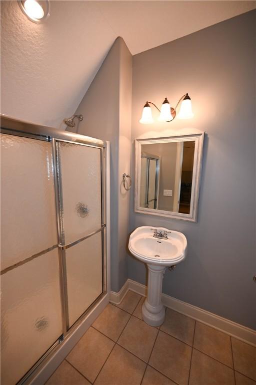 bathroom featuring tile patterned flooring, vaulted ceiling, and an enclosed shower