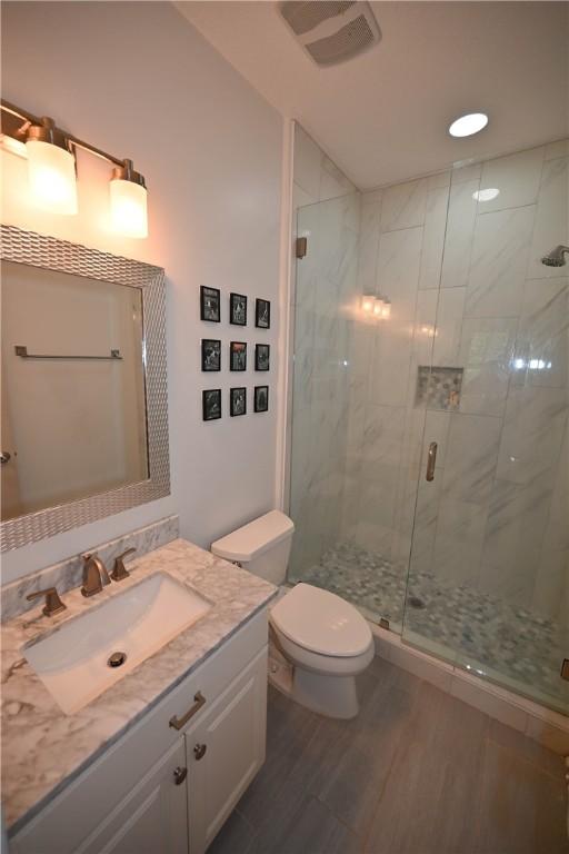 bathroom featuring toilet, vanity, wood-type flooring, and walk in shower