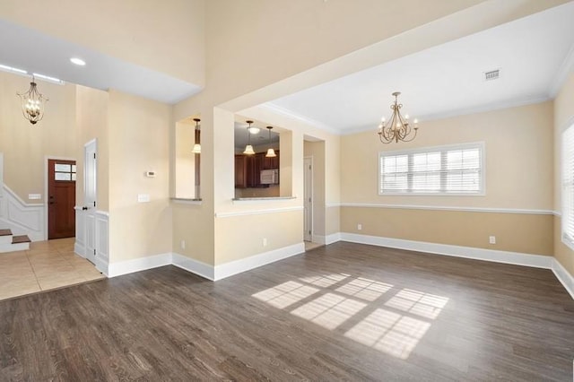 spare room with an inviting chandelier, ornamental molding, and dark wood-type flooring