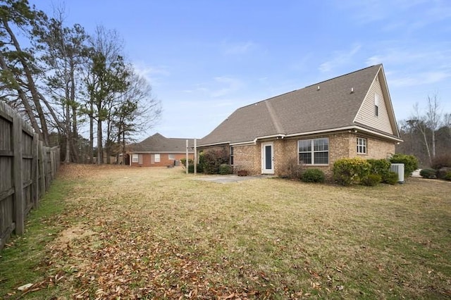 back of property featuring a lawn and central air condition unit