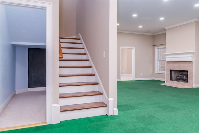 stairs with carpet, crown molding, and a tiled fireplace