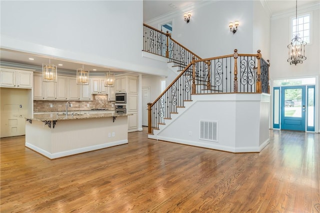 kitchen featuring pendant lighting, decorative backsplash, ornamental molding, light stone counters, and stainless steel appliances