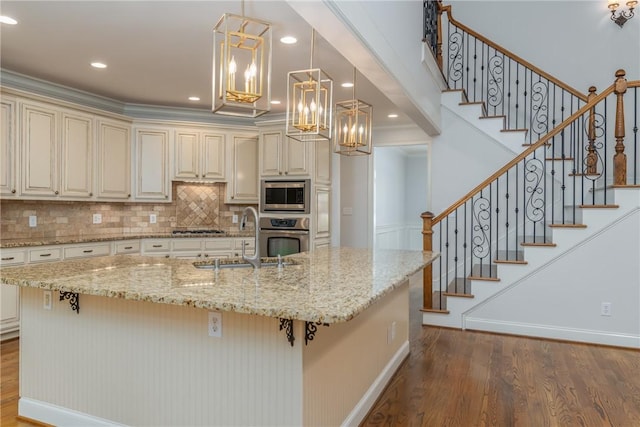 kitchen featuring light stone countertops, appliances with stainless steel finishes, cream cabinetry, and sink