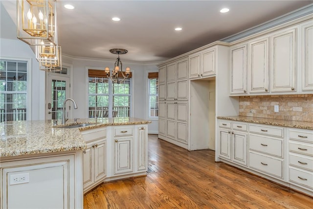 kitchen featuring decorative backsplash, light stone counters, sink, and pendant lighting