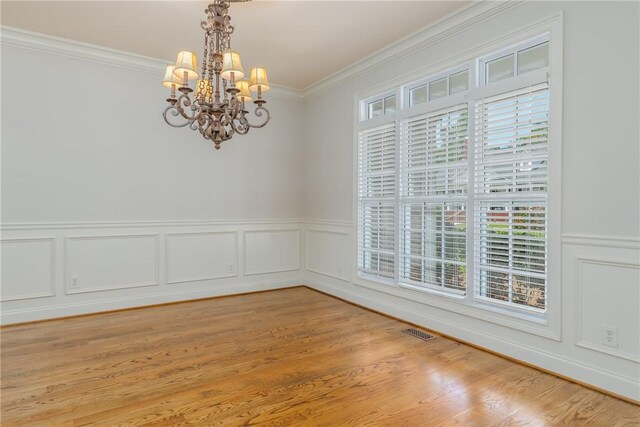 unfurnished room featuring light hardwood / wood-style floors, crown molding, a healthy amount of sunlight, and a notable chandelier