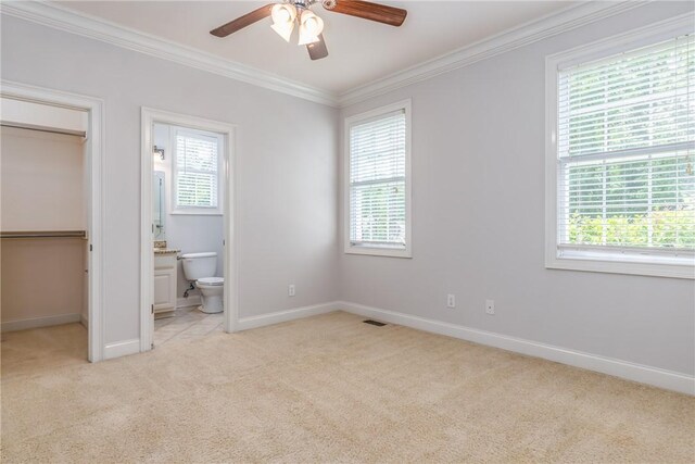 unfurnished bedroom featuring ceiling fan, ornamental molding, ensuite bathroom, and multiple windows