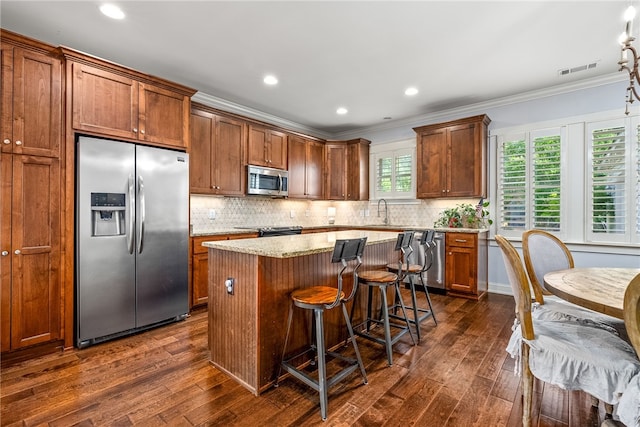 3515 Double Eagle Ln, Opelika, AL 36801 - kitchen with appliances with stainless steel finishes, crown molding, a kitchen island, dark wood-type flooring, and decorative backsplash