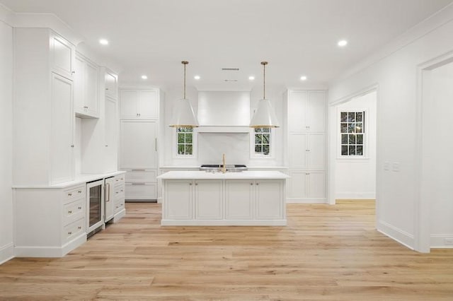 kitchen featuring sink, an island with sink, white cabinets, and hanging light fixtures