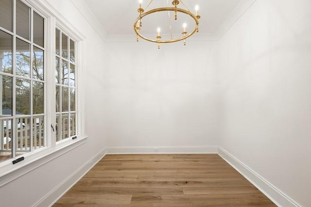 unfurnished dining area with wood-type flooring, an inviting chandelier, and ornamental molding