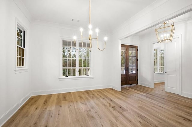 unfurnished dining area with french doors, ornamental molding, light hardwood / wood-style floors, and a notable chandelier