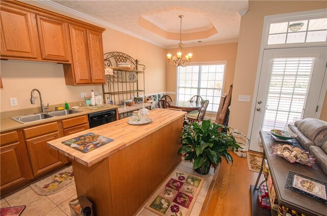 kitchen with a raised ceiling, crown molding, sink, butcher block countertops, and a kitchen island