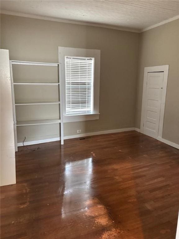 empty room featuring ornamental molding, baseboards, and wood finished floors