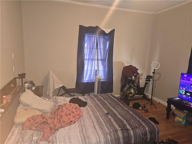 bedroom with crown molding, baseboards, and wood finished floors