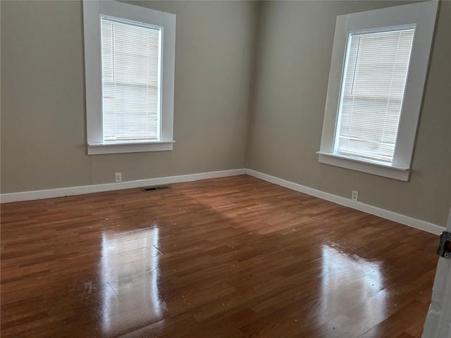 empty room with visible vents, baseboards, and wood finished floors