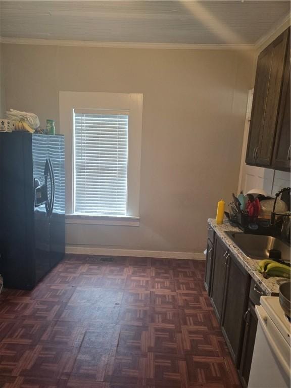 kitchen with dark brown cabinetry, black fridge, crown molding, and a sink