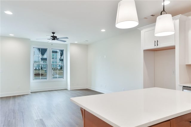 kitchen with white cabinetry, a center island, ceiling fan, hanging light fixtures, and dark hardwood / wood-style floors