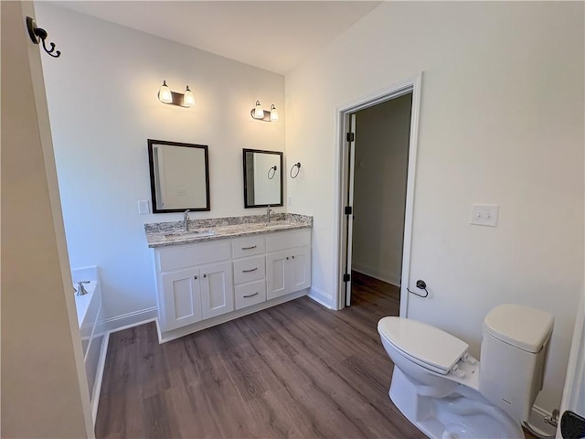 bathroom with hardwood / wood-style flooring, toilet, a bathing tub, and vanity