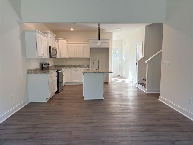 kitchen with a kitchen island with sink, light stone countertops, appliances with stainless steel finishes, dark hardwood / wood-style flooring, and white cabinetry