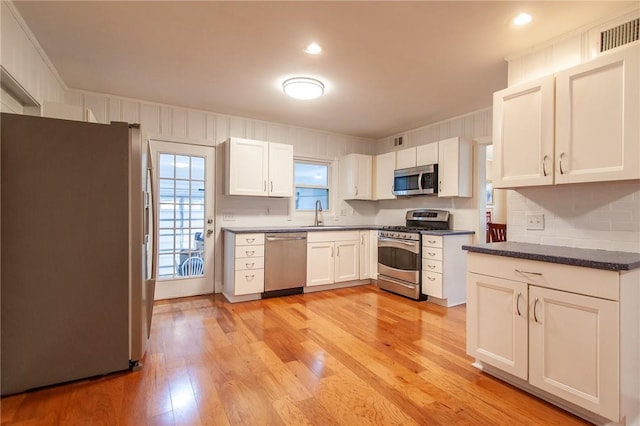 kitchen featuring backsplash, stainless steel appliances, sink, light hardwood / wood-style flooring, and white cabinetry