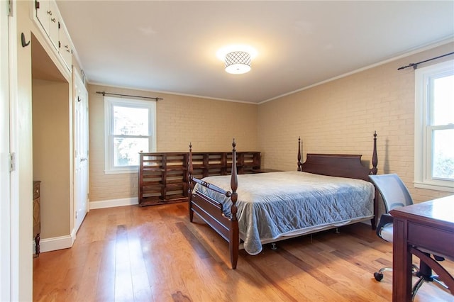 bedroom featuring wood-type flooring, ornamental molding, and brick wall