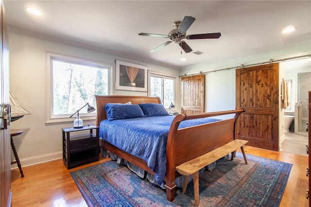 bedroom featuring ensuite bath, ceiling fan, a barn door, ornamental molding, and light hardwood / wood-style floors