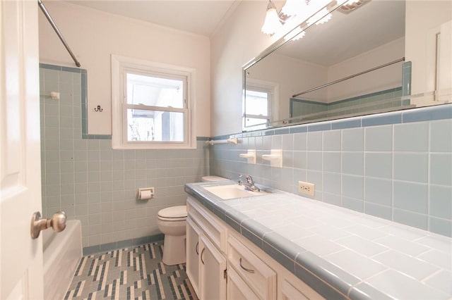 bathroom with tile patterned floors, ornamental molding, vanity, tile walls, and toilet