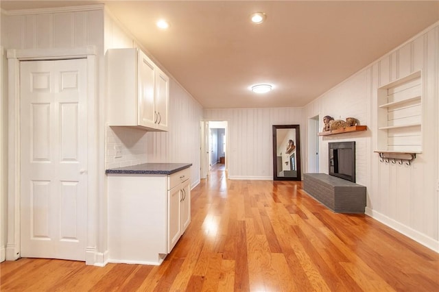 kitchen featuring a fireplace, built in shelves, light hardwood / wood-style floors, and white cabinetry