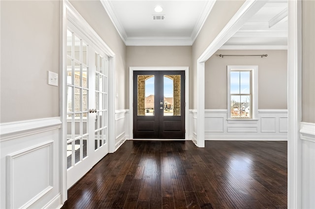 foyer entrance featuring visible vents, a wainscoted wall, ornamental molding, dark wood-type flooring, and french doors