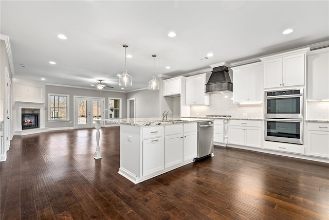 kitchen with dark wood-style flooring, tasteful backsplash, double oven, open floor plan, and premium range hood