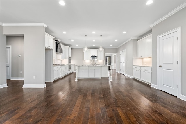 kitchen with dark wood-style flooring, custom range hood, stainless steel microwave, and decorative backsplash