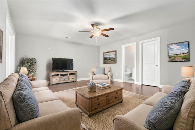 living area with wood finished floors, a ceiling fan, and baseboards