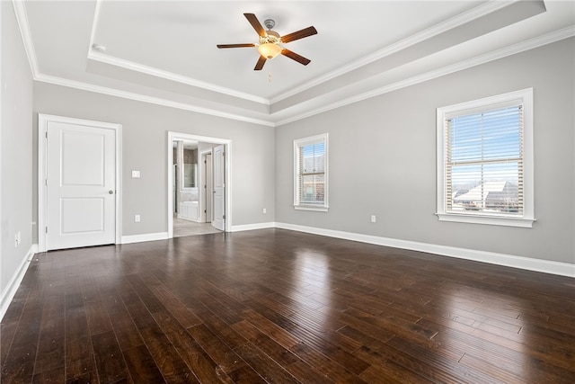 unfurnished bedroom with a tray ceiling, multiple windows, and hardwood / wood-style flooring