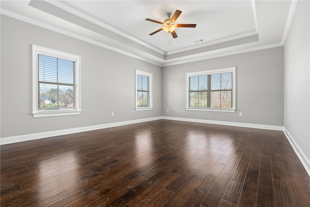 spare room with dark wood-style floors, a raised ceiling, visible vents, and baseboards