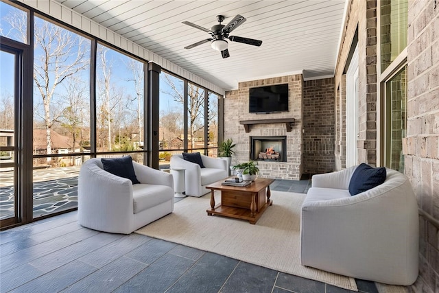 sunroom featuring an outdoor brick fireplace, wooden ceiling, and a ceiling fan