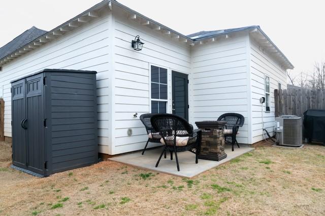 back of house with an outbuilding, a patio, a lawn, central AC unit, and fence