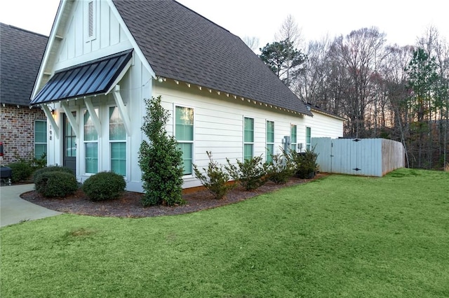 view of property exterior featuring a standing seam roof, a lawn, and a shingled roof