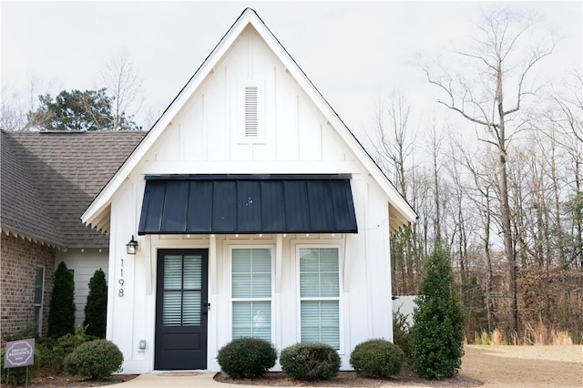 view of front facade featuring metal roof, roof with shingles, board and batten siding, and a standing seam roof