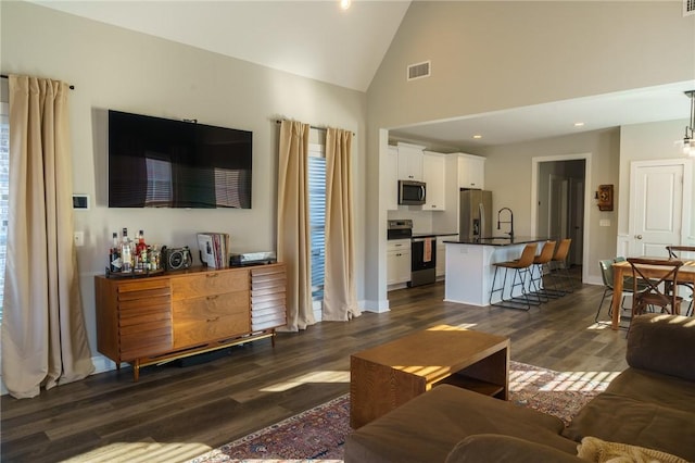 living room with visible vents, dark wood-type flooring, high vaulted ceiling, recessed lighting, and baseboards