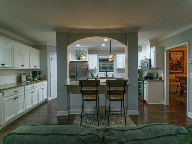 1201 Live Oak Cir, Opelika, AL 36801 - kitchen featuring stainless steel appliances, ornamental molding, white cabinetry, a kitchen bar, and dark wood-style flooring