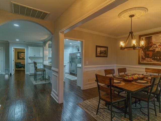 1201 Live Oak Cir, Opelika, AL 36801 - dining space featuring arched walkways, dark wood finished floors, ornamental molding, a wainscoted wall, and a chandelier