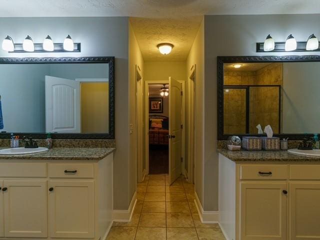 1201 Live Oak Cir, Opelika, AL 36801 - full bath featuring tile patterned floors, a stall shower, two vanities, and baseboards