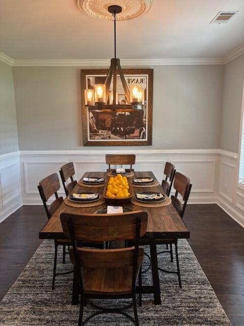 1201 Live Oak Cir, Opelika, AL 36801 - dining room featuring dark wood finished floors, a chandelier, crown molding, a wainscoted wall, and a decorative wall