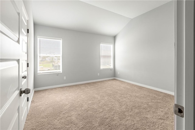 carpeted empty room featuring lofted ceiling