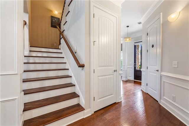 staircase featuring a wainscoted wall, ornamental molding, wood finished floors, and a decorative wall