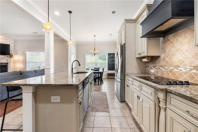 kitchen with stainless steel appliances, a sink, open floor plan, custom range hood, and cream cabinetry